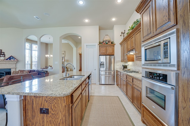 kitchen featuring tasteful backsplash, light tile patterned flooring, stainless steel appliances, light stone counters, and sink