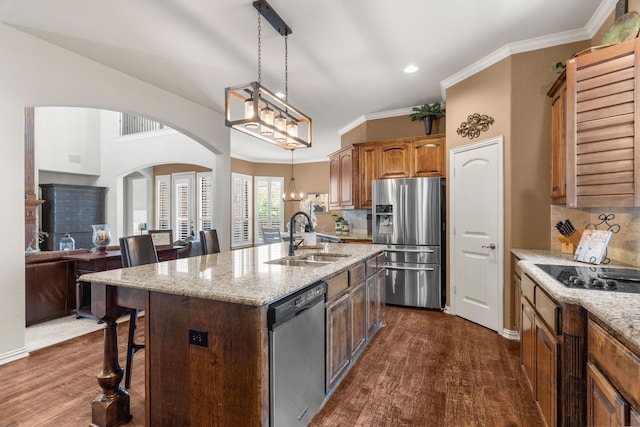 kitchen featuring sink, dark hardwood / wood-style floors, an island with sink, light stone counters, and stainless steel appliances