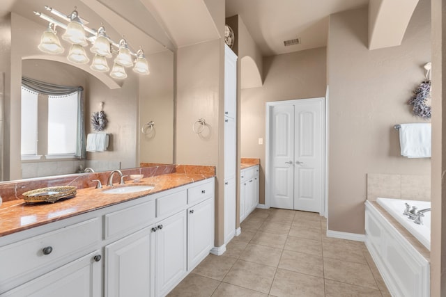 bathroom with tile patterned flooring, vanity, and a bath