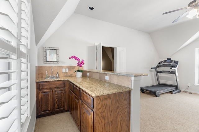 kitchen featuring kitchen peninsula, light carpet, sink, and ceiling fan