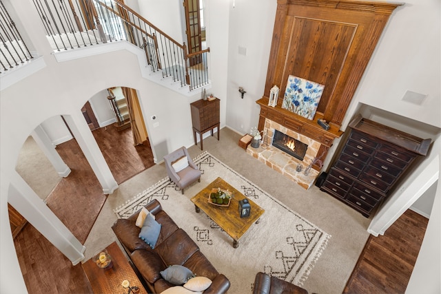 living room featuring a fireplace, wood-type flooring, and a high ceiling