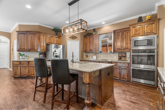 kitchen with appliances with stainless steel finishes, dark hardwood / wood-style flooring, tasteful backsplash, and an island with sink