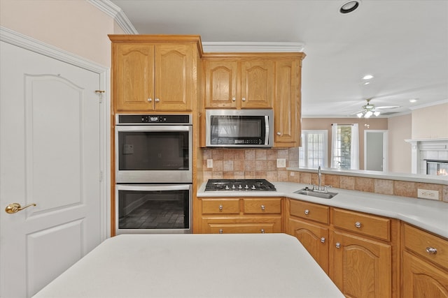 kitchen featuring a tiled fireplace, ornamental molding, appliances with stainless steel finishes, and sink