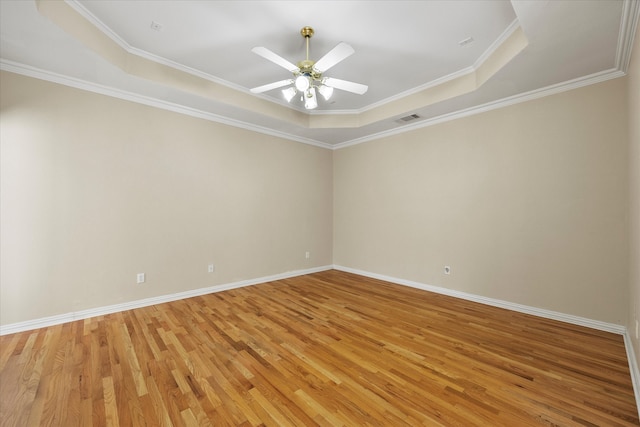 spare room featuring ceiling fan, ornamental molding, a raised ceiling, and wood-type flooring