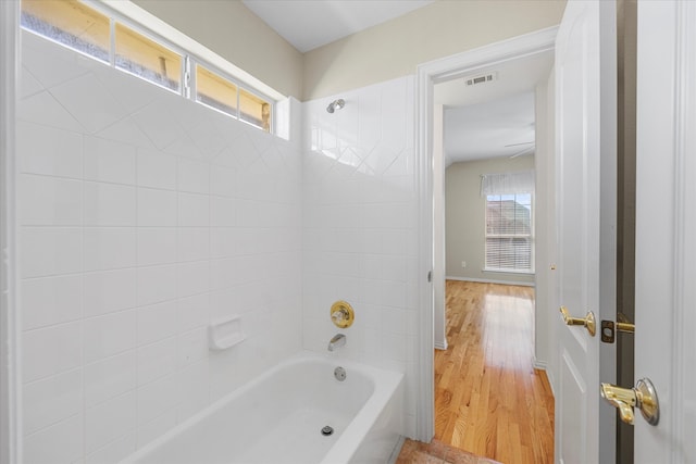 bathroom with wood-type flooring and tiled shower / bath