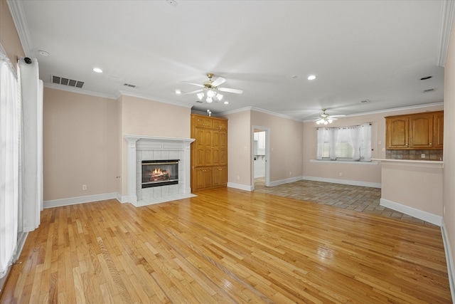 unfurnished living room with light hardwood / wood-style flooring, crown molding, a fireplace, and ceiling fan