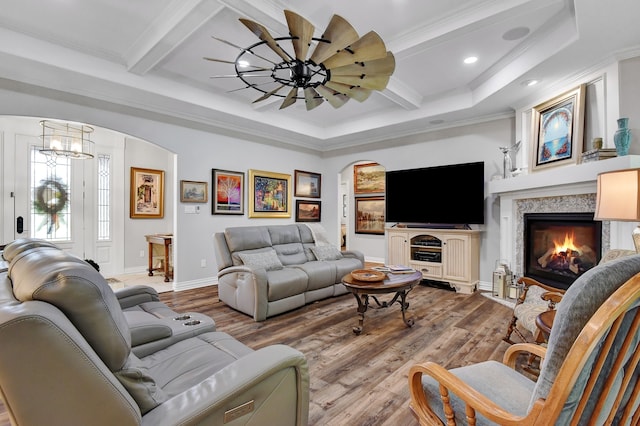 living room with crown molding, a fireplace, beamed ceiling, and hardwood / wood-style flooring