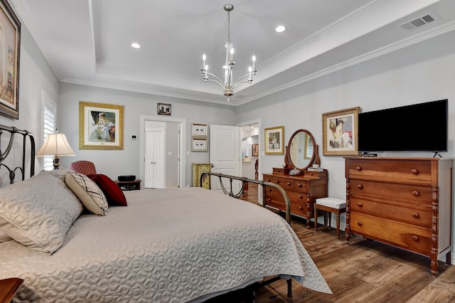 bedroom featuring hardwood / wood-style flooring, a notable chandelier, a raised ceiling, and ornamental molding