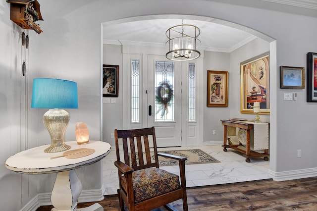 foyer featuring dark hardwood / wood-style flooring, crown molding, and a notable chandelier