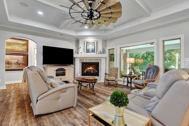 living room with beamed ceiling, light hardwood / wood-style floors, ornamental molding, and a premium fireplace