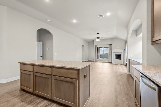 kitchen featuring ceiling fan, dishwasher, light stone counters, light hardwood / wood-style flooring, and a kitchen island