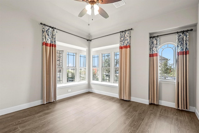 empty room with hardwood / wood-style flooring, ceiling fan, and a healthy amount of sunlight