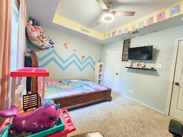 bedroom featuring carpet floors, a tray ceiling, and ceiling fan