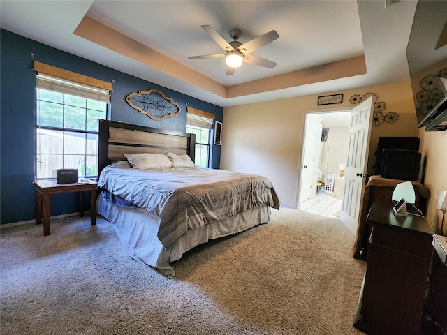 carpeted bedroom with a tray ceiling and ceiling fan