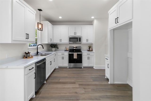 kitchen featuring white cabinetry, hanging light fixtures, sink, stainless steel appliances, and light stone counters