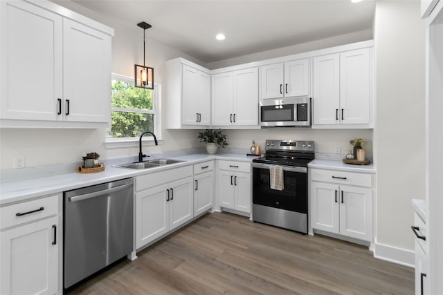 kitchen featuring pendant lighting, sink, white cabinets, dark wood-type flooring, and stainless steel appliances