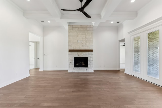 unfurnished living room featuring beam ceiling, a stone fireplace, ceiling fan, and coffered ceiling