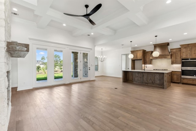 unfurnished living room with beam ceiling, sink, coffered ceiling, ceiling fan with notable chandelier, and hardwood / wood-style flooring