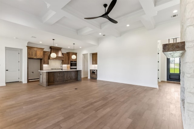 unfurnished living room with ceiling fan, beamed ceiling, wood-type flooring, and coffered ceiling