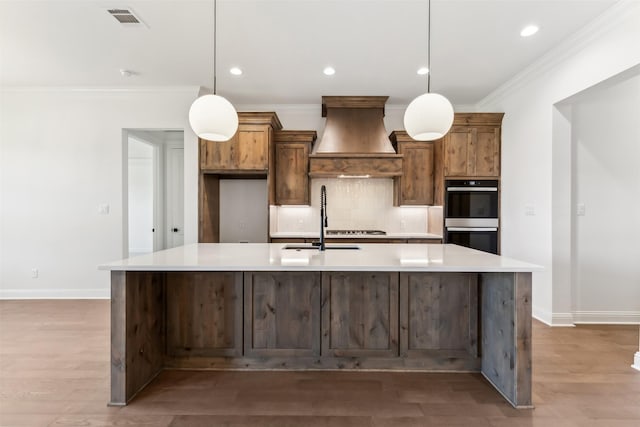 kitchen featuring a large island, sink, hanging light fixtures, stainless steel double oven, and custom exhaust hood