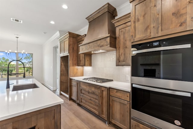 kitchen with sink, an inviting chandelier, decorative light fixtures, custom range hood, and appliances with stainless steel finishes