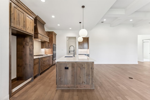 kitchen featuring pendant lighting, a center island with sink, sink, beam ceiling, and stainless steel gas cooktop