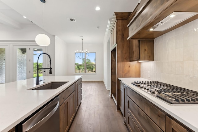 kitchen featuring custom exhaust hood, an inviting chandelier, sink, hanging light fixtures, and stainless steel appliances