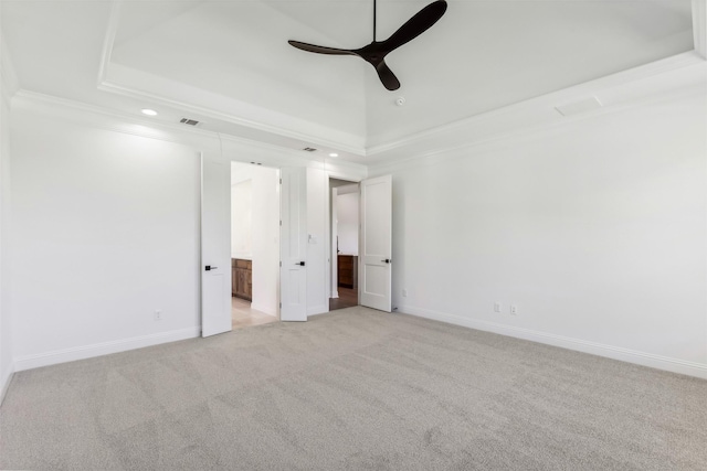 carpeted empty room with a tray ceiling, ceiling fan, and ornamental molding