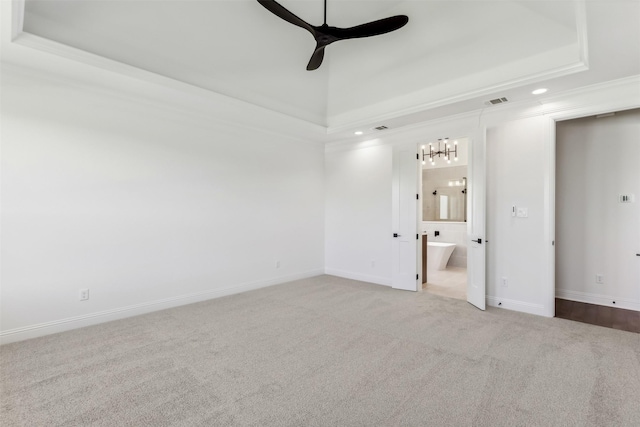 unfurnished bedroom with light carpet, ornamental molding, a tray ceiling, ceiling fan, and connected bathroom