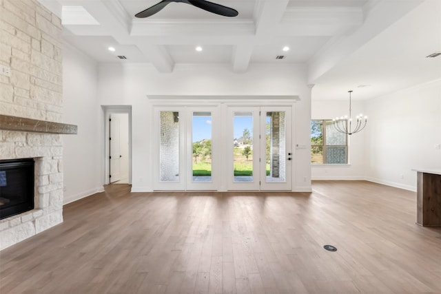 unfurnished living room featuring coffered ceiling, ceiling fan with notable chandelier, hardwood / wood-style flooring, a fireplace, and beam ceiling