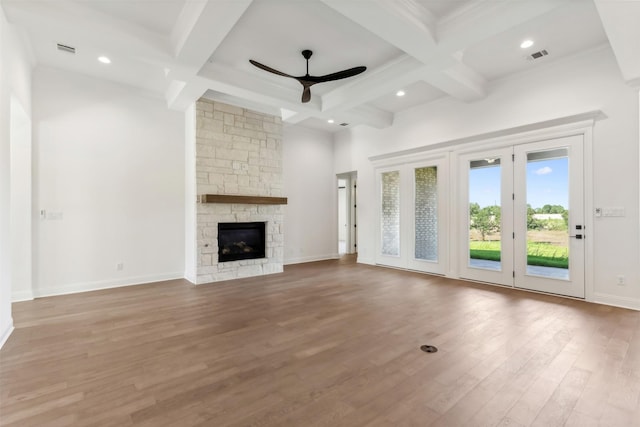 unfurnished living room featuring ceiling fan, coffered ceiling, light hardwood / wood-style flooring, beamed ceiling, and a fireplace