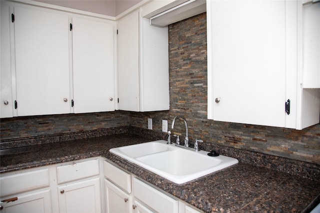 kitchen featuring sink, dark stone counters, backsplash, and white cabinetry