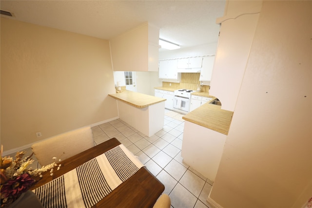 kitchen featuring light tile patterned floors, decorative backsplash, white cabinetry, kitchen peninsula, and white electric range