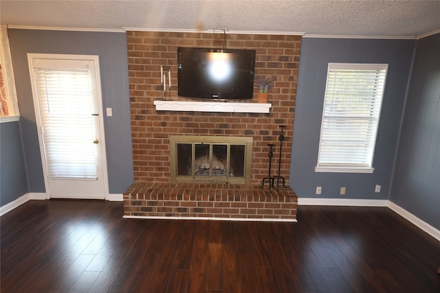 unfurnished living room featuring dark hardwood / wood-style flooring, a fireplace, a textured ceiling, and crown molding