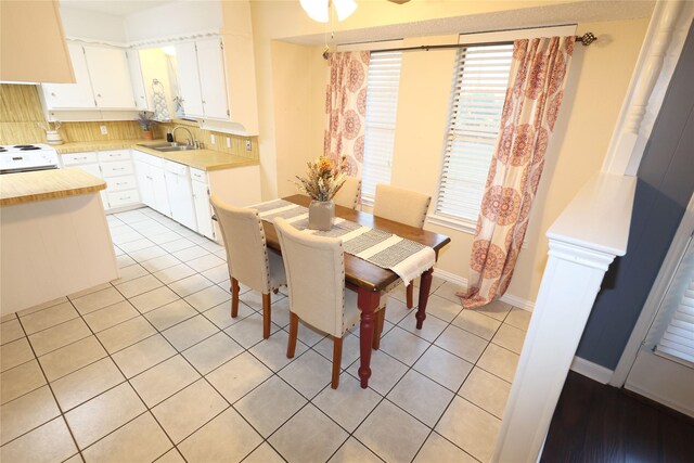 dining space with light tile patterned flooring, sink, and ceiling fan