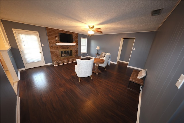 living room featuring hardwood / wood-style floors, a fireplace, a textured ceiling, ceiling fan, and brick wall