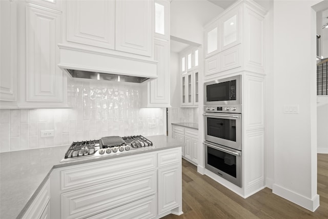 kitchen featuring custom exhaust hood, dark hardwood / wood-style floors, appliances with stainless steel finishes, and white cabinetry