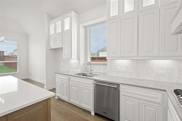 kitchen featuring wood-type flooring, stainless steel dishwasher, sink, decorative backsplash, and white cabinetry