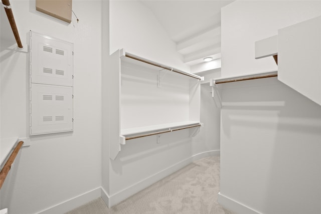 spacious closet with light colored carpet and vaulted ceiling