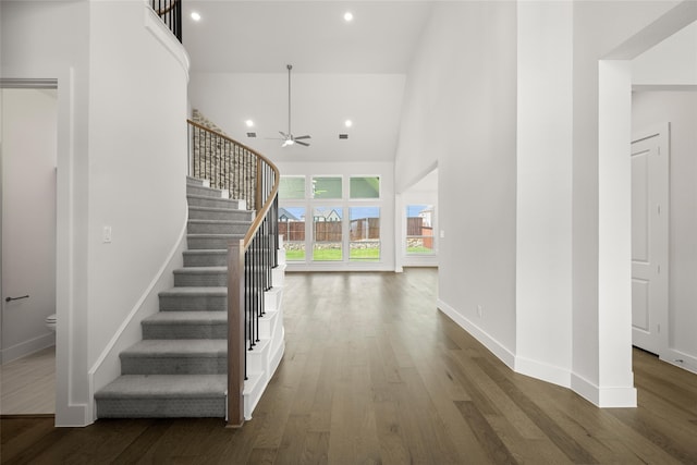 entryway with a towering ceiling, ceiling fan, and dark hardwood / wood-style floors