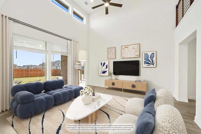 living room featuring hardwood / wood-style flooring, ceiling fan, and a high ceiling