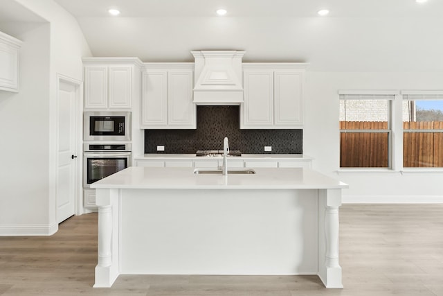 kitchen with white cabinets, oven, light hardwood / wood-style flooring, tasteful backsplash, and black microwave