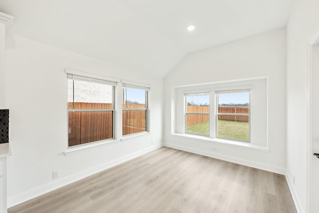 spare room featuring lofted ceiling and light hardwood / wood-style floors