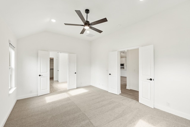 unfurnished bedroom featuring ceiling fan, light carpet, and vaulted ceiling