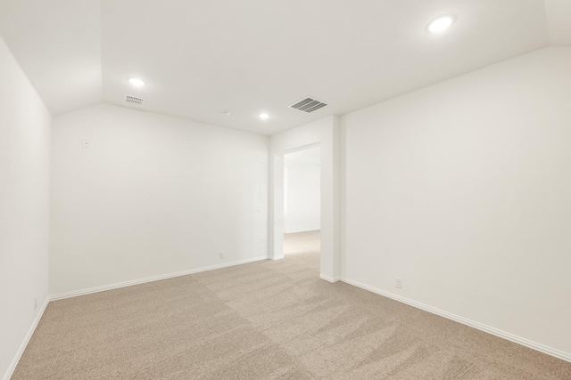 carpeted empty room featuring vaulted ceiling