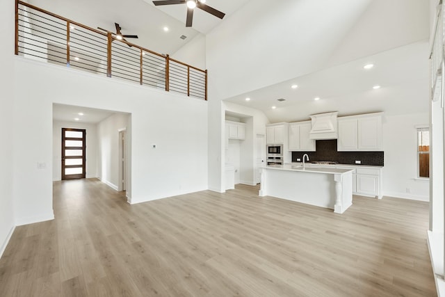 kitchen featuring white cabinetry, light hardwood / wood-style floors, a center island with sink, and a wealth of natural light