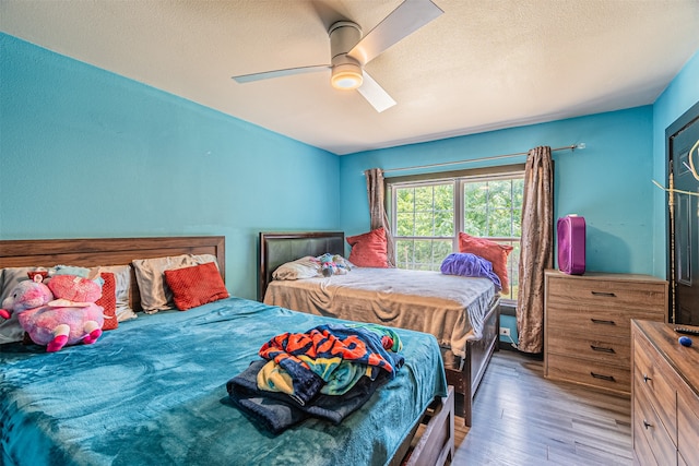 bedroom featuring ceiling fan, light wood-type flooring, and a textured ceiling