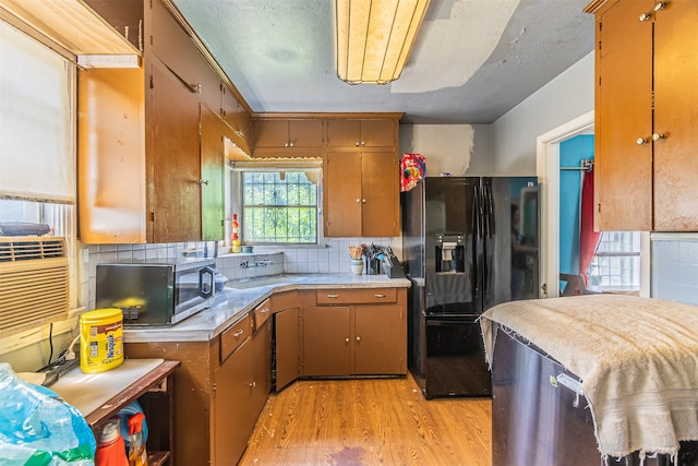 kitchen featuring light hardwood / wood-style flooring, black refrigerator with ice dispenser, sink, and backsplash