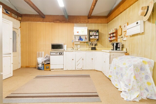 kitchen featuring beam ceiling, white dishwasher, and wood walls