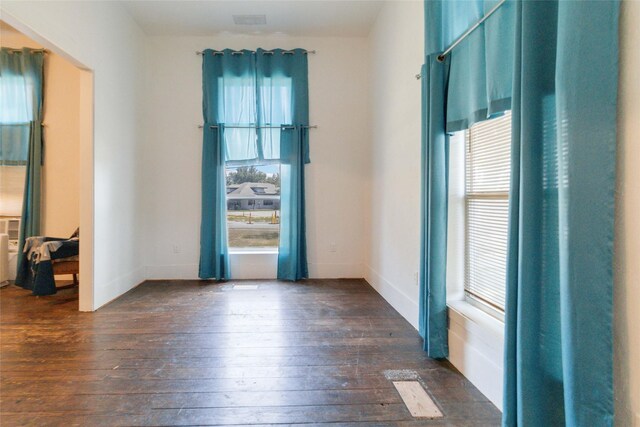 empty room featuring dark wood-type flooring and a wealth of natural light